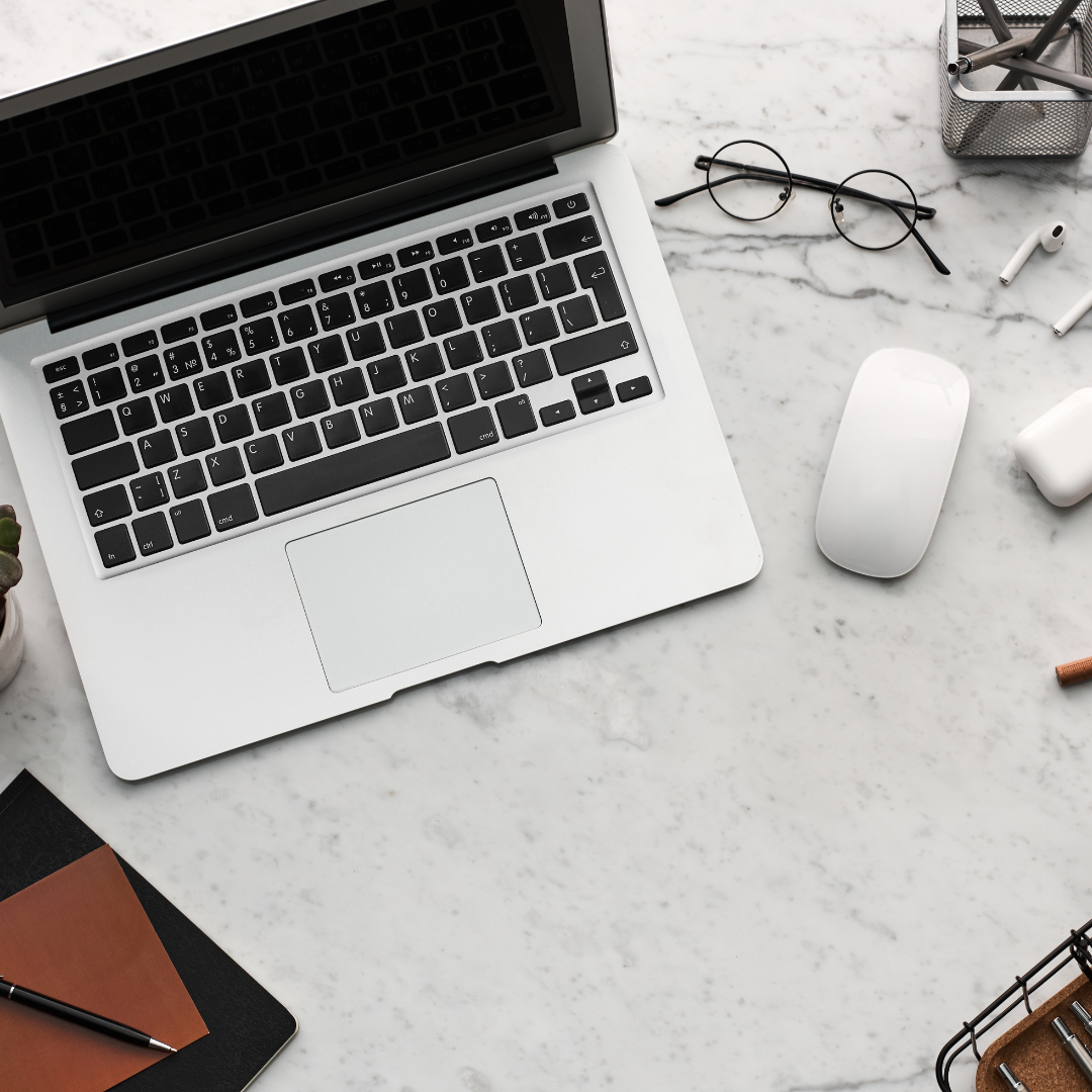 The macbook and accessories of a digital marketing consultant on a pretty white marble table